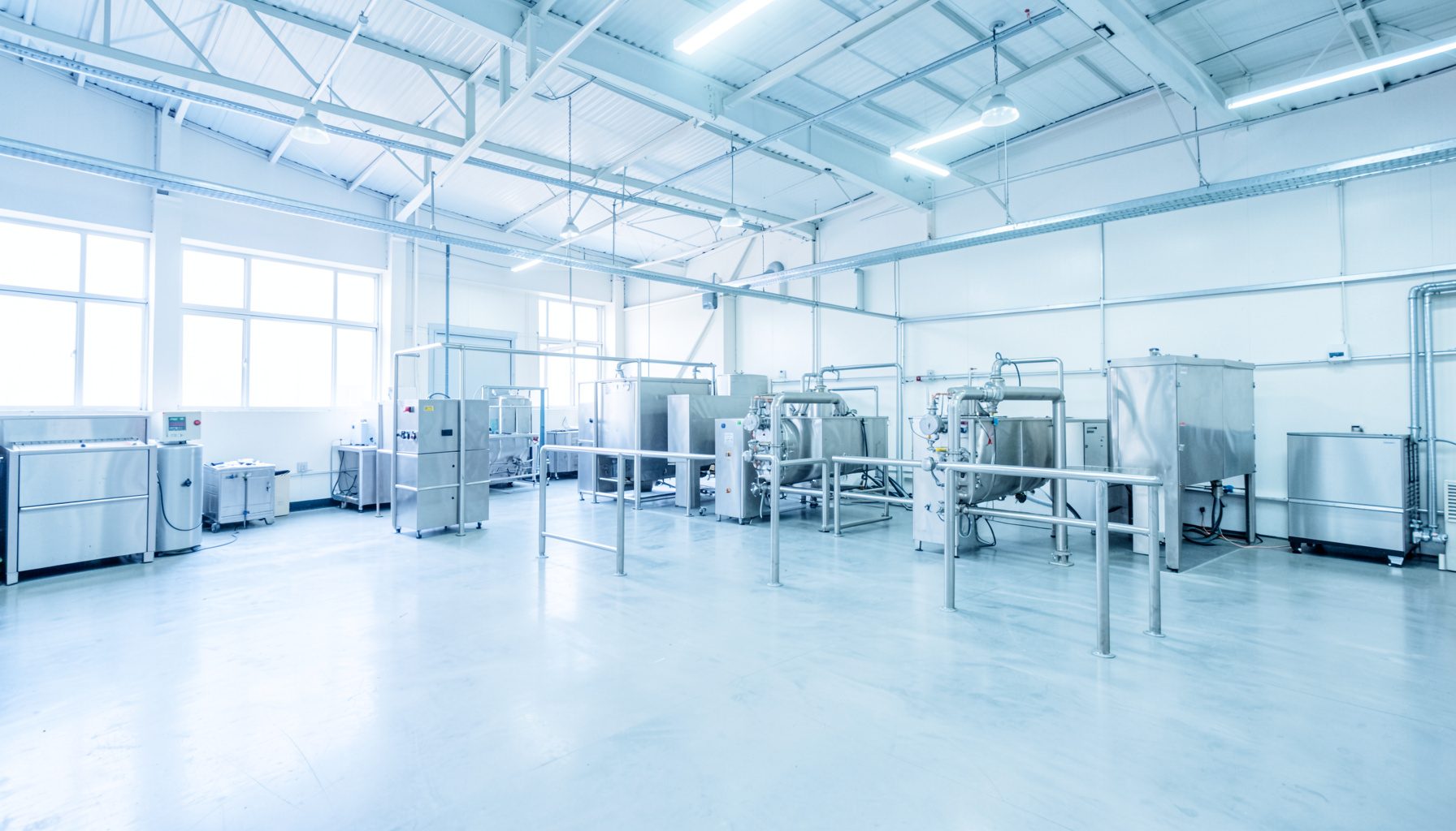 Wide industrial workshop interior with stainless steel drying machinery, bright overhead lighting, and clean concrete floors